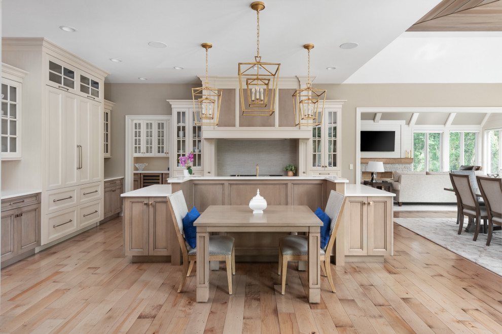 Inspiration for a transitional u-shaped eat-in kitchen in Chicago with recessed-panel cabinets, white cabinets, quartz benchtops, beige splashback, medium hardwood floors, with island, brown floor, white benchtop and wood.