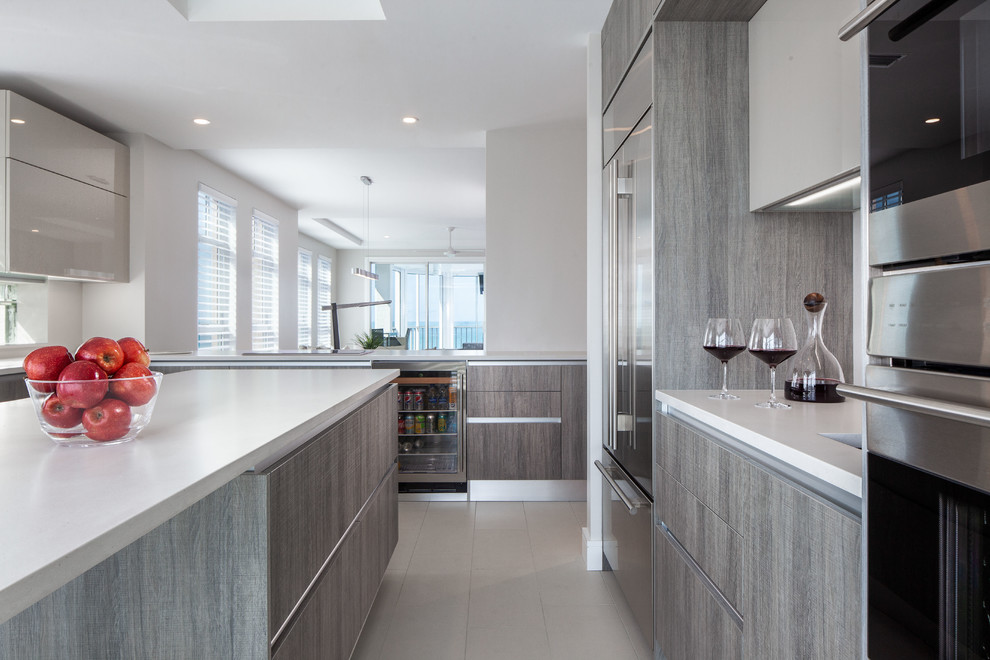 Photo of a mid-sized modern l-shaped eat-in kitchen in Miami with a single-bowl sink, flat-panel cabinets, grey cabinets, quartz benchtops, white splashback, window splashback, stainless steel appliances, ceramic floors, with island, beige floor and white benchtop.