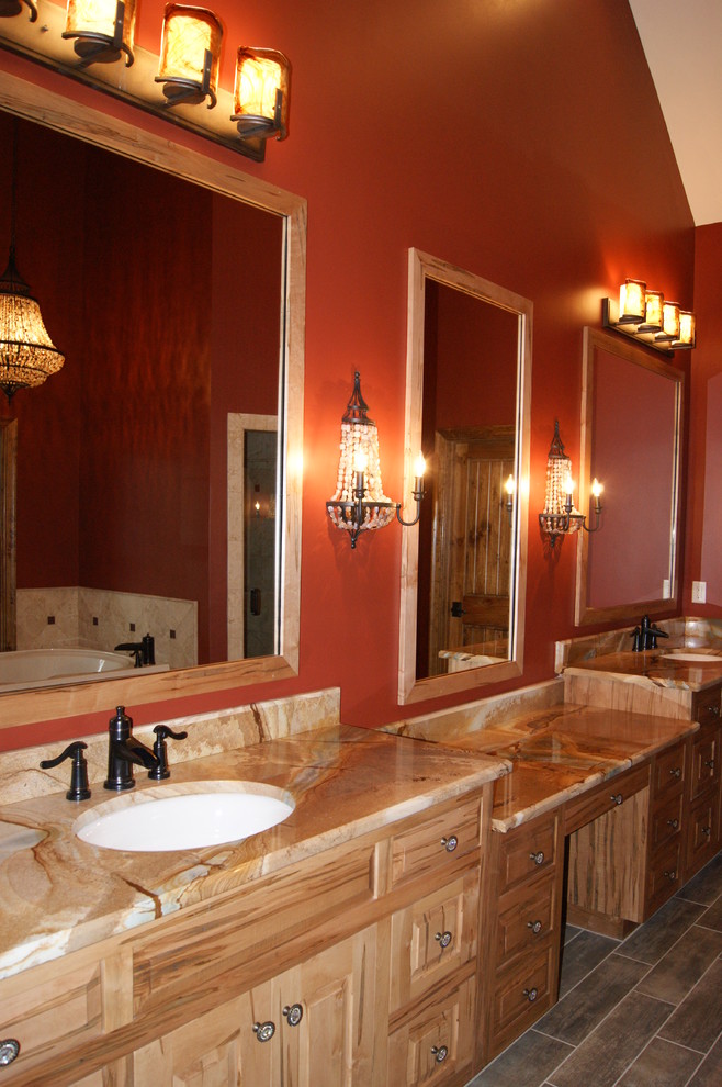 Example of a large master drop-in bathtub design in Atlanta with an undermount sink, raised-panel cabinets, light wood cabinets, marble countertops and red walls