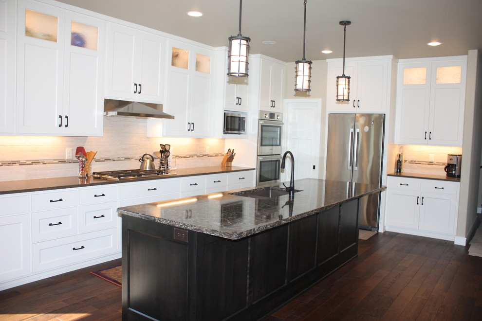 Example of a mid-sized transitional l-shaped dark wood floor open concept kitchen design with an undermount sink, recessed-panel cabinets, white cabinets, quartz countertops, beige backsplash, ceramic backsplash, stainless steel appliances and an island