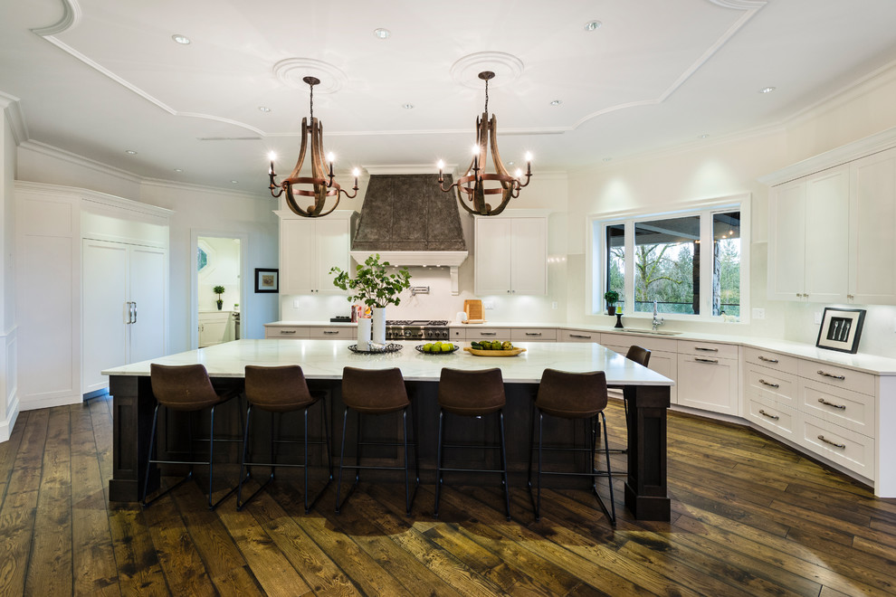 Inspiration for a huge rustic u-shaped medium tone wood floor and brown floor open concept kitchen remodel in Vancouver with an undermount sink, shaker cabinets, white cabinets, solid surface countertops, white backsplash, stone slab backsplash, stainless steel appliances, an island and white countertops