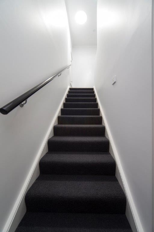 Small contemporary carpeted straight staircase in Canberra - Queanbeyan with carpet risers and metal railing.