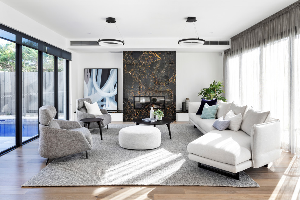 This is an example of a large contemporary formal open concept living room in Melbourne with white walls, medium hardwood floors, a ribbon fireplace, no tv, brown floor and a stone fireplace surround.