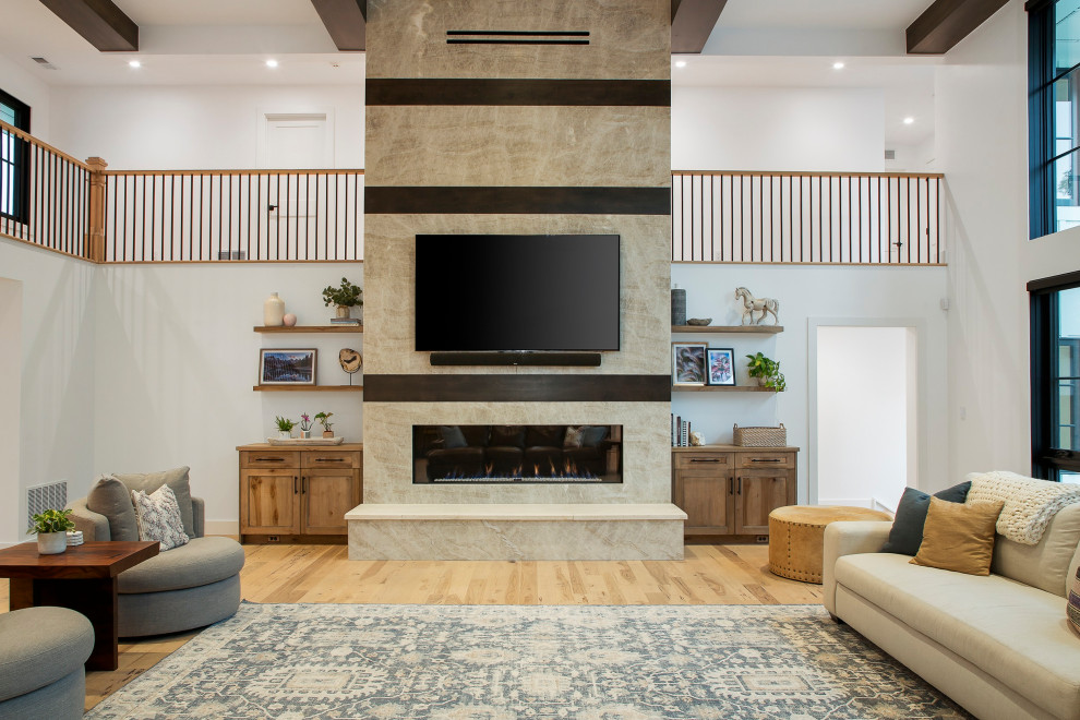 Inspiration for an expansive country open plan living room in Denver with white walls, light hardwood flooring, a ribbon fireplace, a stone fireplace surround, a wall mounted tv, white floors and exposed beams.