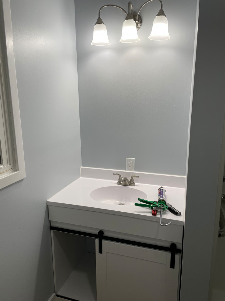 Small country powder room in Other with shaker cabinets, white cabinets, a one-piece toilet, grey walls, vinyl floors, a drop-in sink, brown floor, white benchtops and a freestanding vanity.