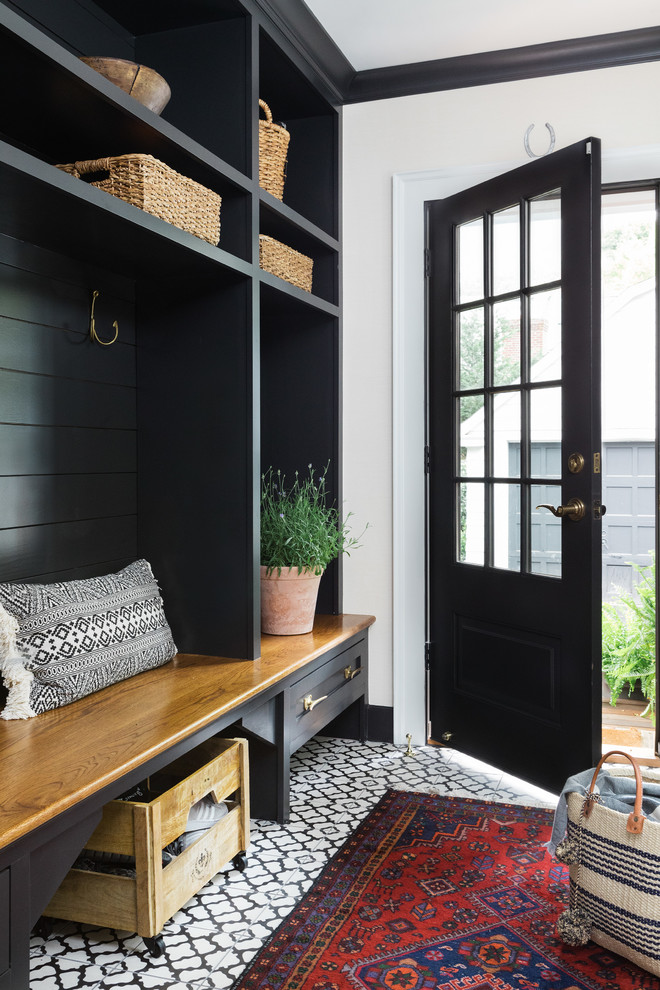 Design ideas for a mid-sized country mudroom in Boston with white walls, ceramic floors and a black front door.