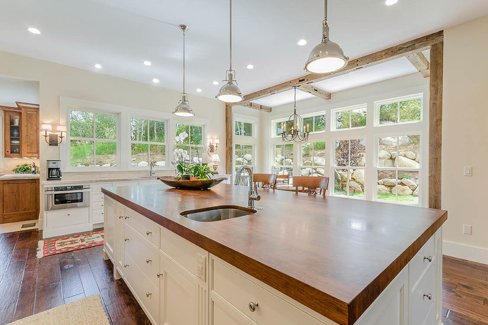 Example of a huge transitional l-shaped dark wood floor and brown floor eat-in kitchen design with an undermount sink, shaker cabinets, white cabinets, wood countertops, gray backsplash, matchstick tile backsplash, stainless steel appliances and an island