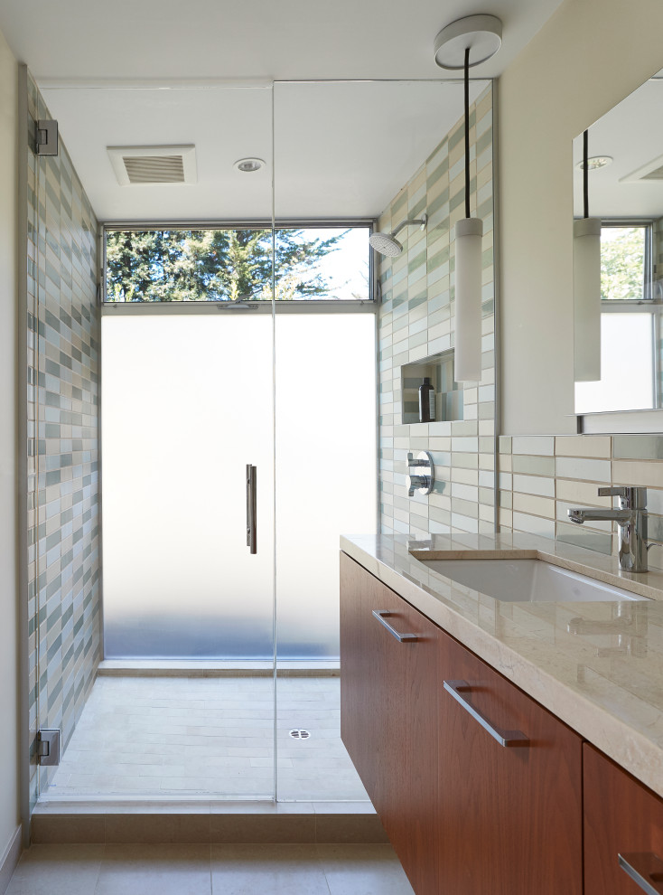 This is an example of a midcentury bathroom in San Francisco with flat-panel cabinets, medium wood cabinets, an alcove shower, multi-coloured tile, beige walls, an undermount sink, beige floor, beige benchtops and a floating vanity.