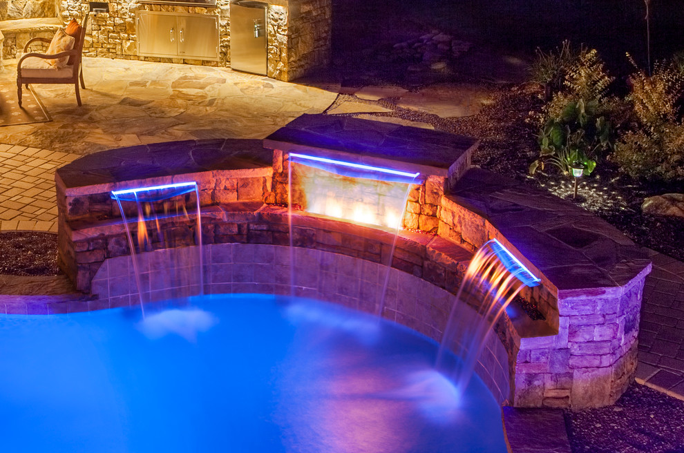 Example of a backyard stone and custom-shaped lap hot tub design in Atlanta