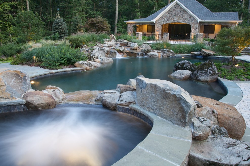 Photo of a large country backyard custom-shaped pool in DC Metro with a hot tub and brick pavers.