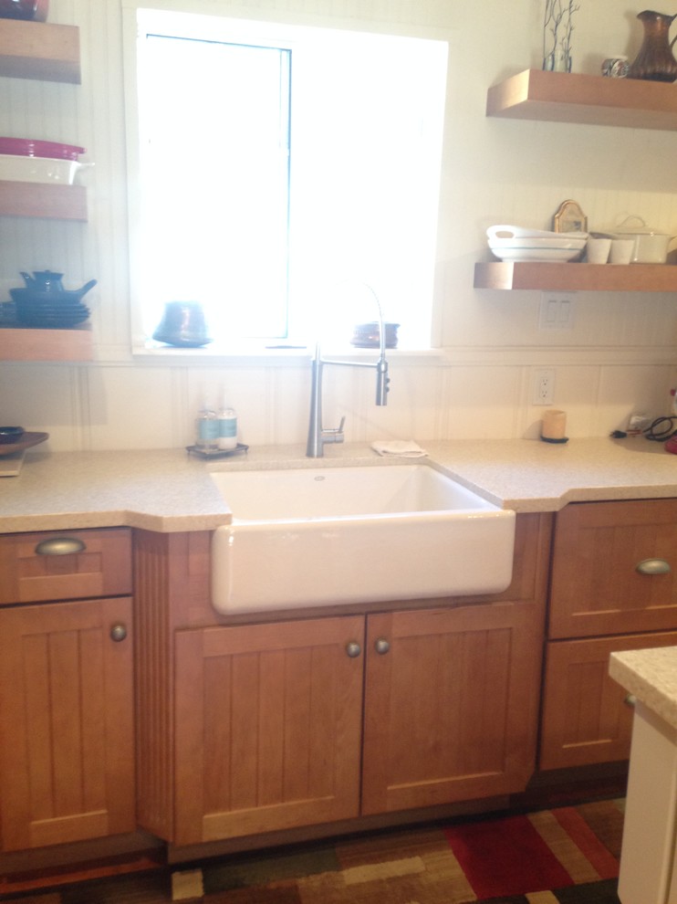 Mid-sized mountain style l-shaped medium tone wood floor open concept kitchen photo with a farmhouse sink, beaded inset cabinets, light wood cabinets, solid surface countertops, beige backsplash, glass tile backsplash, stainless steel appliances and an island