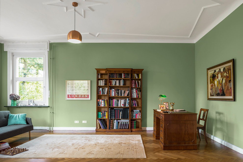 Réalisation d'un bureau tradition avec un mur vert, un sol en bois brun et un sol marron.