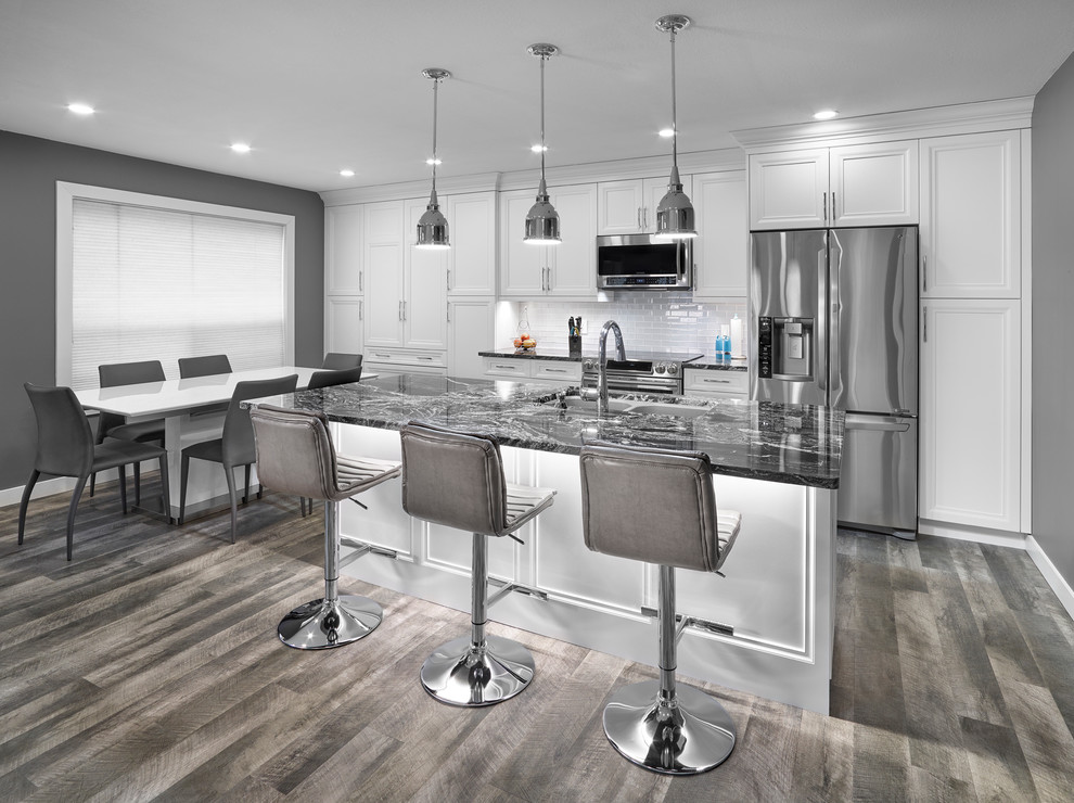 Inspiration for a mid-sized transitional galley vinyl floor and gray floor eat-in kitchen remodel in Edmonton with an undermount sink, recessed-panel cabinets, white cabinets, granite countertops, white backsplash, subway tile backsplash, stainless steel appliances and an island