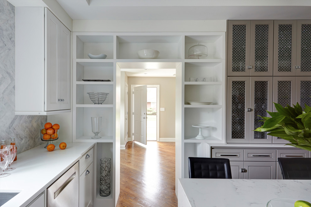 Example of a mid-sized transitional u-shaped medium tone wood floor eat-in kitchen design in Chicago with an undermount sink, shaker cabinets, white cabinets, solid surface countertops, blue backsplash, stone tile backsplash, stainless steel appliances and an island
