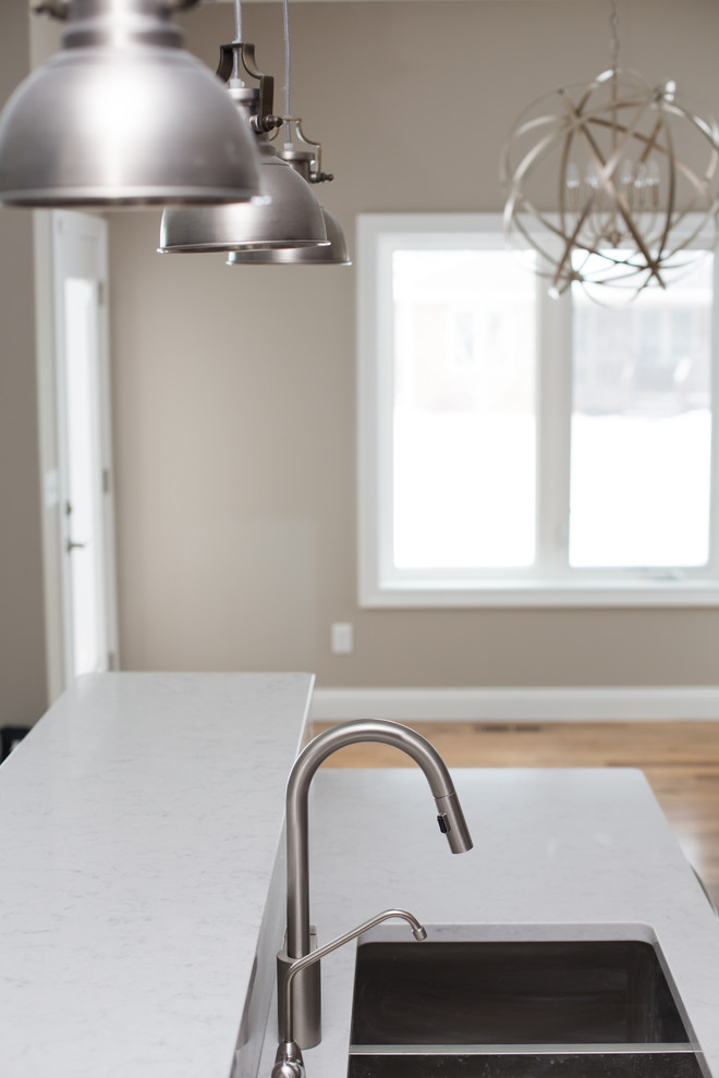 Mid-sized transitional l-shaped dark wood floor enclosed kitchen photo with a double-bowl sink, shaker cabinets, dark wood cabinets, quartz countertops, gray backsplash, stone tile backsplash, stainless steel appliances and an island