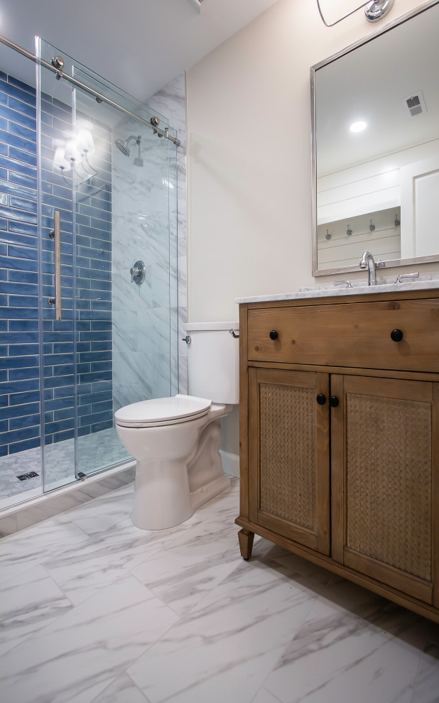 This is an example of an expansive traditional bathroom in DC Metro with freestanding cabinets, light wood cabinets, a two-piece toilet, blue tiles, metro tiles, white walls, porcelain flooring, a submerged sink, marble worktops, white floors, a hinged door, white worktops, a shower bench, a single sink and a freestanding vanity unit.