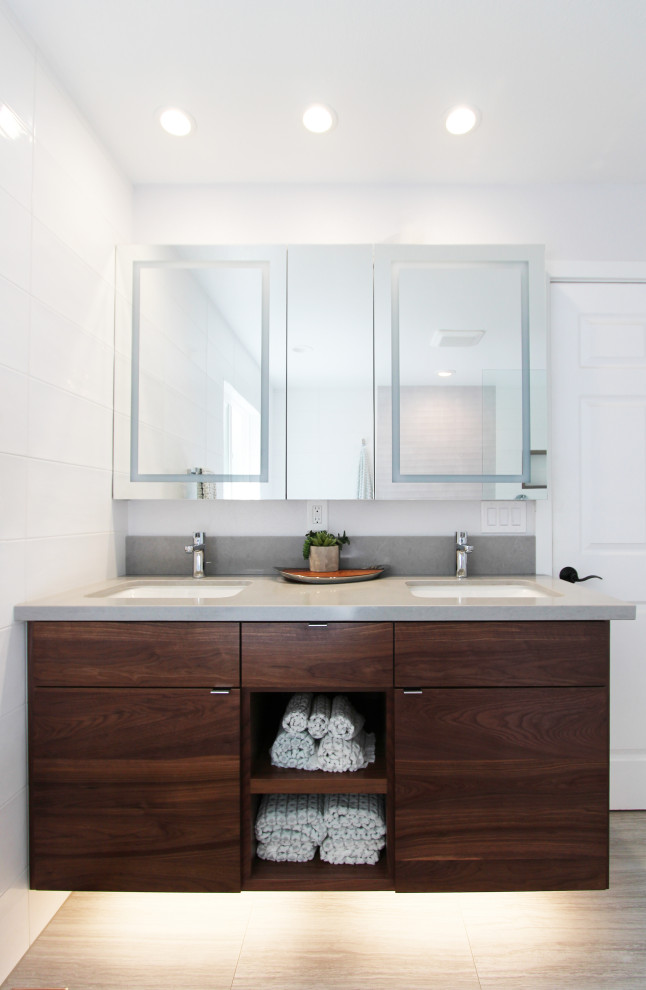 Example of a large transitional master white tile and ceramic tile porcelain tile, gray floor and double-sink freestanding bathtub design with flat-panel cabinets, dark wood cabinets, a one-piece toilet, white walls, an undermount sink, quartz countertops, gray countertops, a niche and a floating vanity