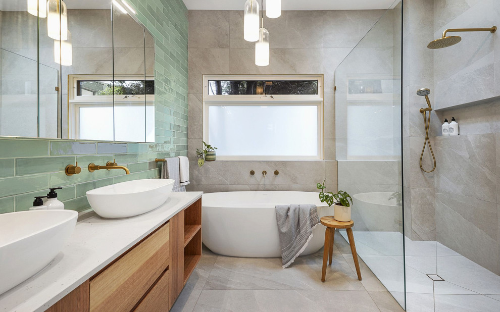 Large transitional master green tile and ceramic tile porcelain tile, gray floor and double-sink freestanding bathtub photo in Melbourne with flat-panel cabinets, medium tone wood cabinets, a one-piece toilet, gray walls, a vessel sink, terrazzo countertops, gray countertops, a niche and a floating vanity