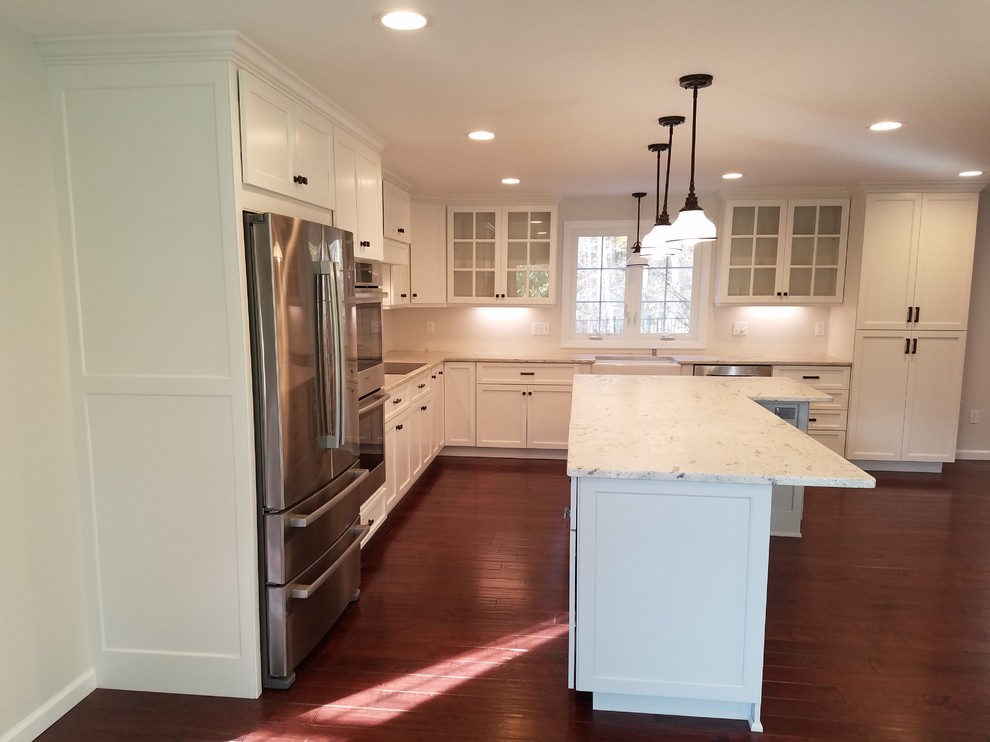 Example of a mid-sized transitional l-shaped dark wood floor and brown floor eat-in kitchen design with a farmhouse sink, shaker cabinets, white cabinets, granite countertops, white backsplash, subway tile backsplash, stainless steel appliances and an island