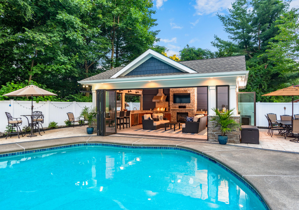 Photo of a mid-sized beach style backyard rectangular natural pool in New York with a pool house and concrete slab.