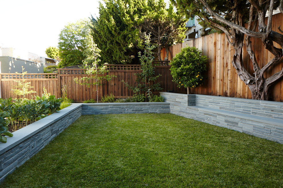 This is an example of a small contemporary backyard partial sun garden for summer in San Francisco with a vegetable garden, natural stone pavers and a wood fence.