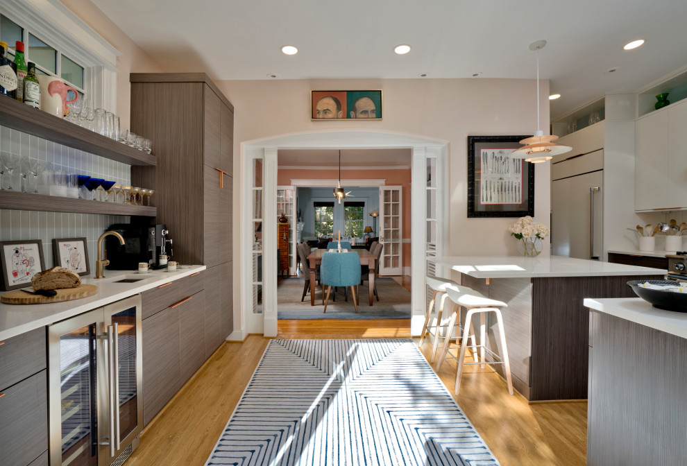 Foto på ett mellanstort retro vit kök, med en undermonterad diskho, släta luckor, skåp i mörkt trä, bänkskiva i kvarts, vitt stänkskydd, stänkskydd i tunnelbanekakel, integrerade vitvaror, ljust trägolv, en halv köksö och brunt golv