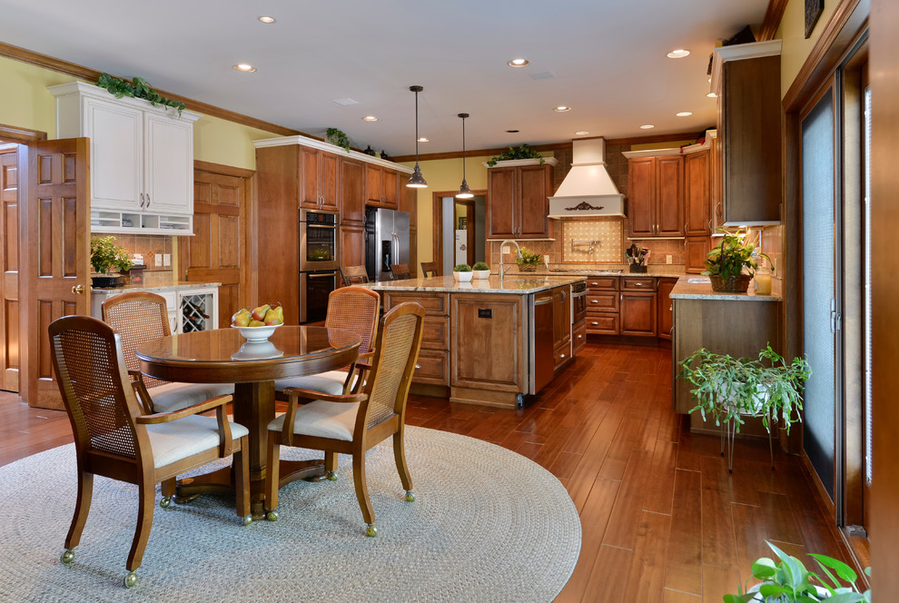 Large transitional u-shaped medium tone wood floor eat-in kitchen photo with beaded inset cabinets, medium tone wood cabinets, granite countertops, beige backsplash, mosaic tile backsplash, stainless steel appliances and an island