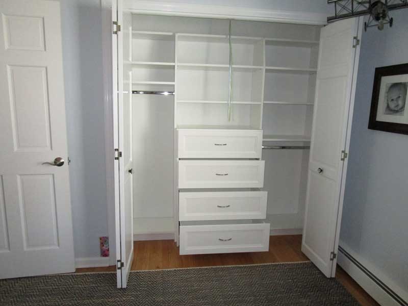 Photo of a small contemporary men's built-in wardrobe in Other with white cabinets, medium hardwood floors and brown floor.