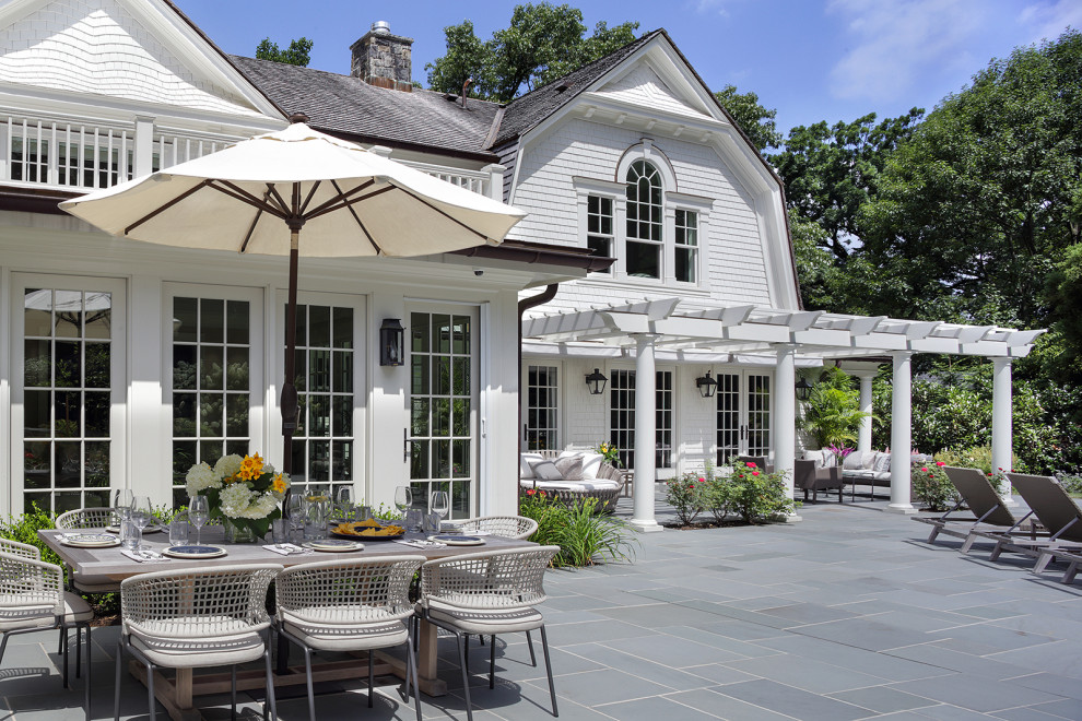 Outdoor Living III - Large elegant backyard stone patio kitchen photo in New York with a pergola