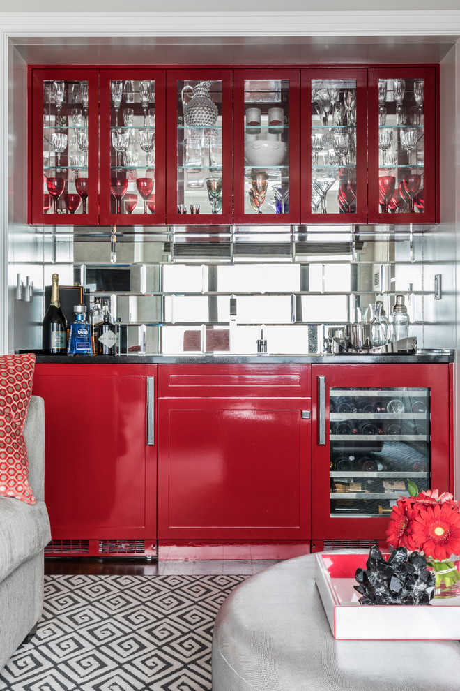 This is an example of a transitional single-wall wet bar in New York with glass-front cabinets, red cabinets and mirror splashback.