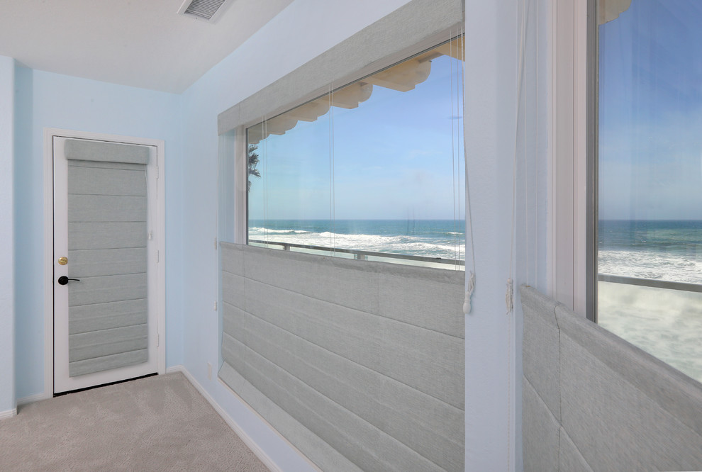 Photo of a beach style master bedroom in San Diego with blue walls, carpet, beige floor and no fireplace.