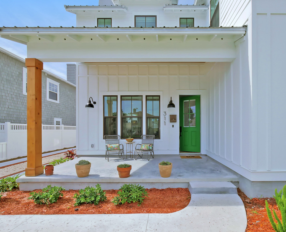 This is an example of a beach style front door in Jacksonville with white walls, concrete floors, a single front door, a green front door and grey floor.