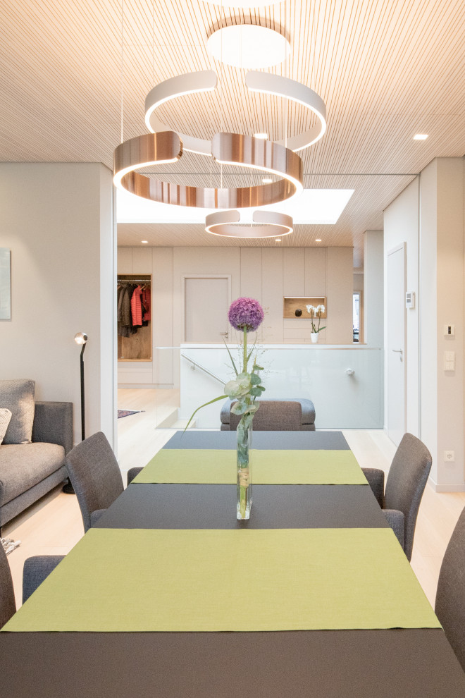 Idée de décoration pour une salle à manger ouverte sur la cuisine design de taille moyenne avec un mur beige, parquet clair, une cheminée d'angle, un manteau de cheminée en plâtre, un sol beige et un plafond en bois.