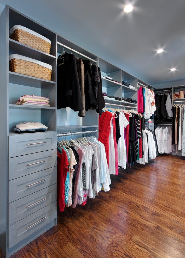 Design ideas for a large traditional gender-neutral walk-in wardrobe in New York with shaker cabinets, grey cabinets, medium hardwood floors and brown floor.