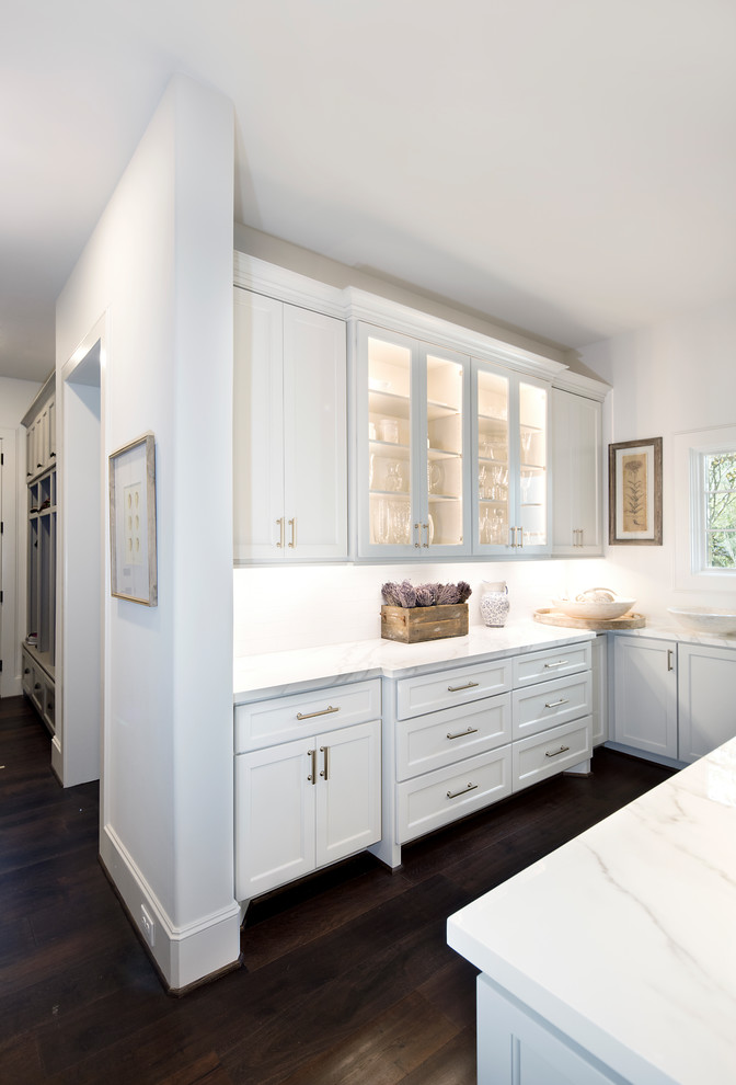 Design ideas for an expansive traditional u-shaped wet bar in Houston with glass-front cabinets, white cabinets, marble benchtops, white splashback and white benchtop.