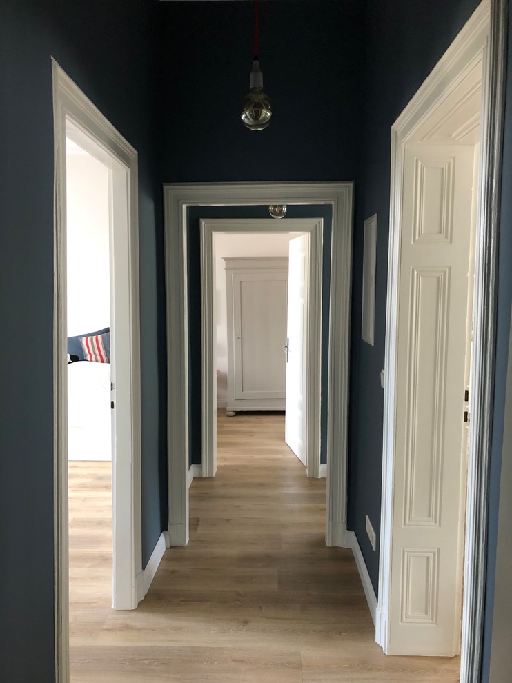 Photo of a mid-sized contemporary hallway in Other with blue walls, light hardwood floors and beige floor.