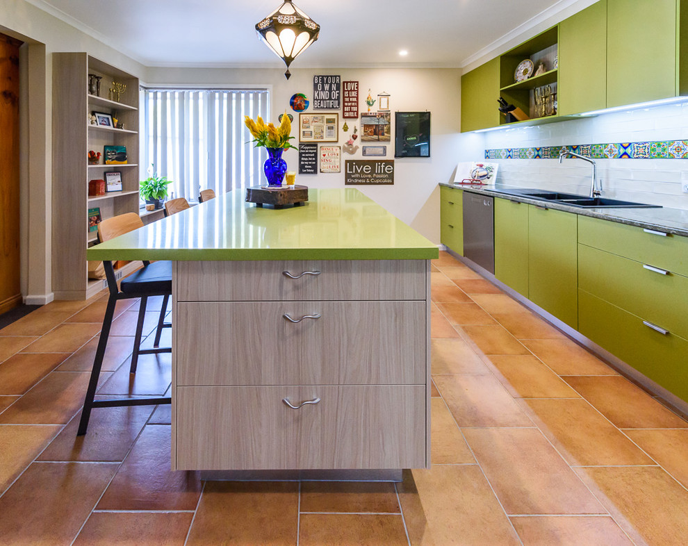 This is an example of a mid-sized eclectic kitchen in Melbourne with a drop-in sink, flat-panel cabinets, green cabinets, laminate benchtops, multi-coloured splashback, ceramic splashback, ceramic floors, with island and stainless steel appliances.