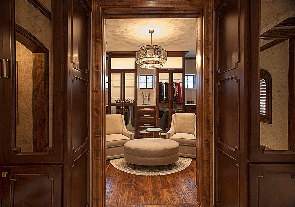 Photo of a large traditional gender-neutral walk-in wardrobe in Dallas with recessed-panel cabinets, dark wood cabinets and medium hardwood floors.