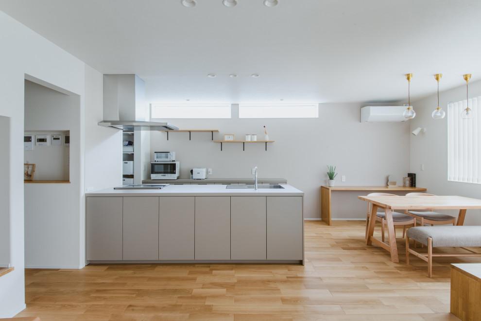 Aménagement d'une cuisine ouverte linéaire campagne avec un évier encastré, une crédence grise, un électroménager blanc, un sol en bois brun, un sol blanc et un plafond en papier peint.