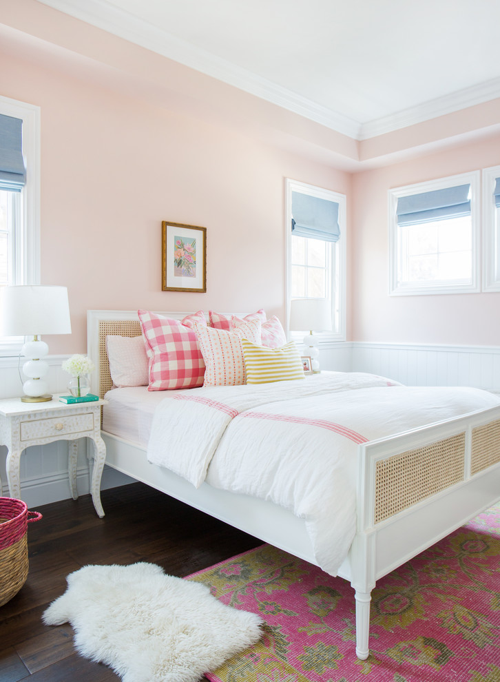 Transitional kids' bedroom in Los Angeles with pink walls and dark hardwood floors for girls.