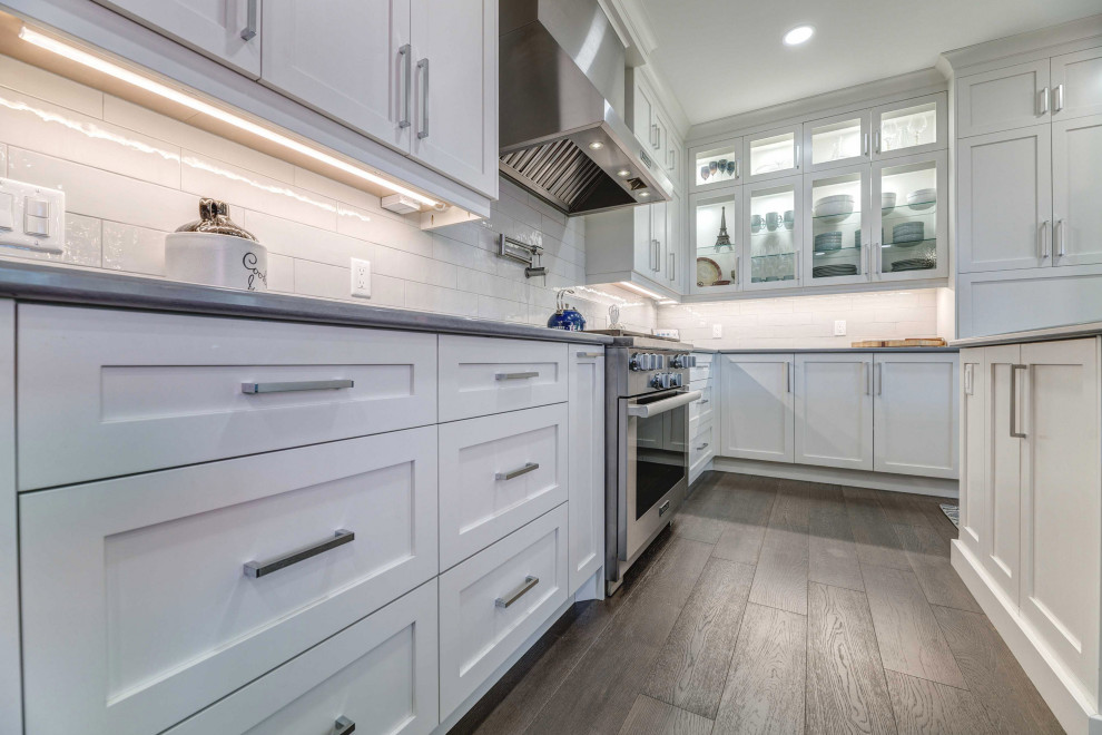 Eat-in kitchen - transitional l-shaped eat-in kitchen idea with a farmhouse sink, shaker cabinets, white cabinets, quartz countertops, porcelain backsplash, stainless steel appliances, an island and white countertops