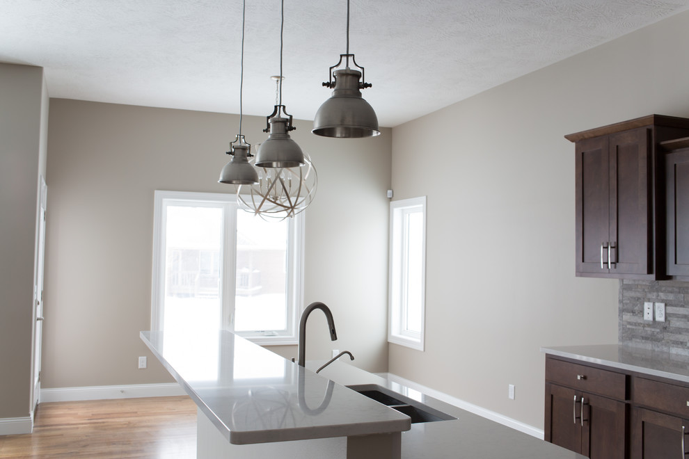 Enclosed kitchen - mid-sized transitional l-shaped dark wood floor enclosed kitchen idea with a double-bowl sink, shaker cabinets, dark wood cabinets, quartz countertops, gray backsplash, stone tile backsplash, stainless steel appliances and an island