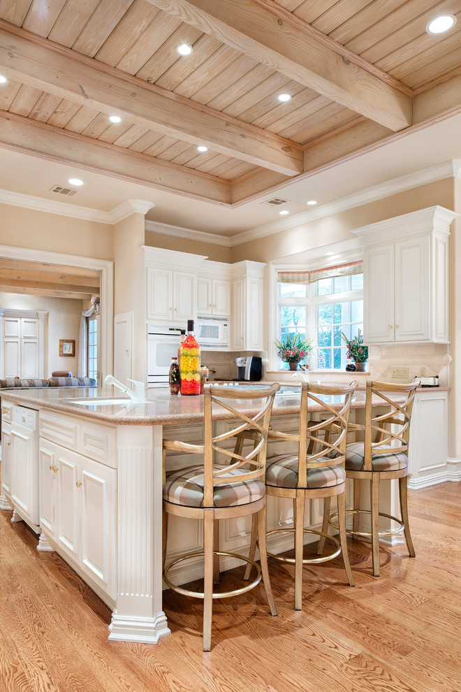 Inspiration for a traditional kitchen in Austin with recessed-panel cabinets, white cabinets, beige splashback, white appliances and medium hardwood floors.