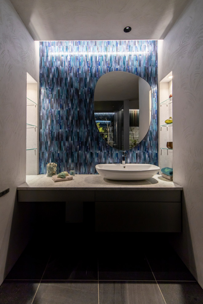 Idéer för stora funkis grått toaletter, med blå kakel, glaskakel, grå väggar, klinkergolv i keramik, ett fristående handfat, bänkskiva i kvarts och svart golv