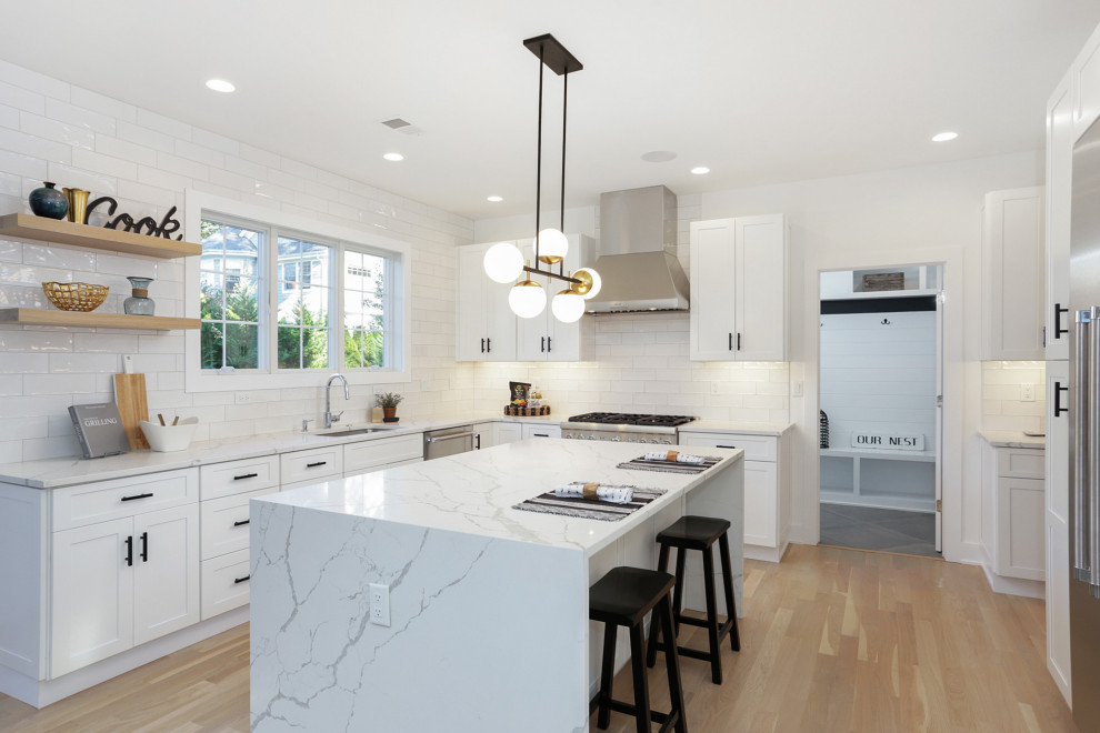 Inspiration for a transitional u-shaped kitchen in New York with an undermount sink, shaker cabinets, white cabinets, white splashback, stainless steel appliances, light hardwood floors, with island, beige floor and white benchtop.