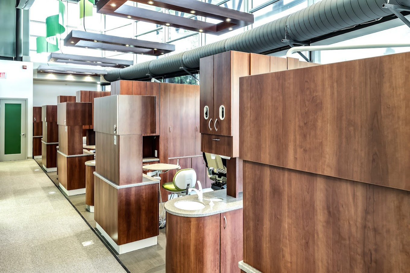 Open-bay operatories with cherry millwork and floating wood ceiling clouds, New Image Dentistry Omaha