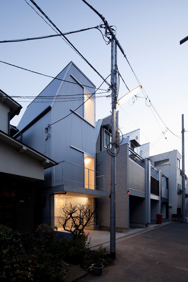 Modern grey house exterior in Tokyo with metal siding, a gambrel roof and a metal roof.