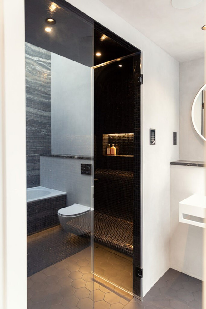 Cette photo montre une salle d'eau scandinave de taille moyenne avec un placard sans porte, des portes de placard beiges, une baignoire posée, un combiné douche/baignoire, un urinoir, un carrelage noir, des carreaux de céramique, un mur noir, un sol en brique, un lavabo posé, un plan de toilette en acier inoxydable, un sol noir, une cabine de douche à porte battante, un plan de toilette beige, meuble double vasque, meuble-lavabo suspendu et un plafond en bois.
