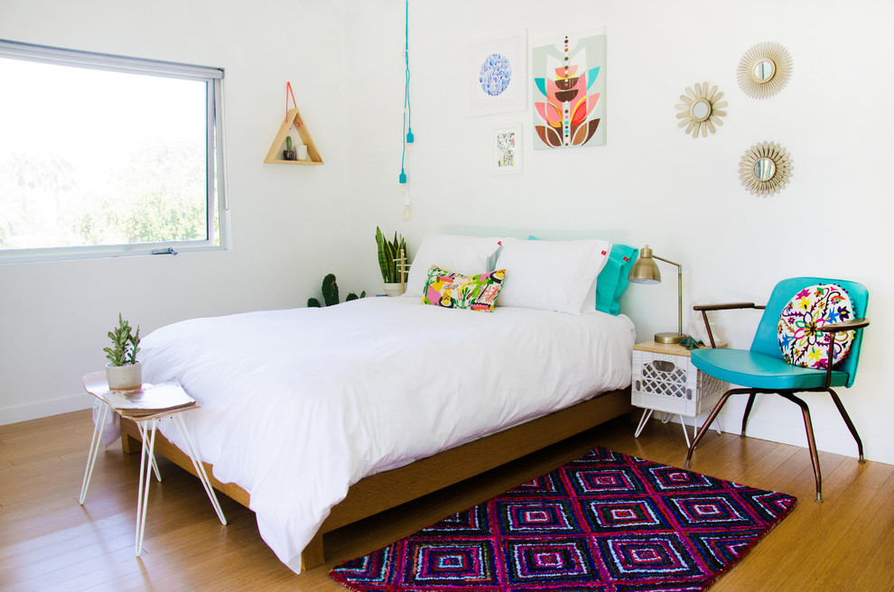 Photo of a mid-sized eclectic bedroom in San Diego with white walls, no fireplace and medium hardwood floors.
