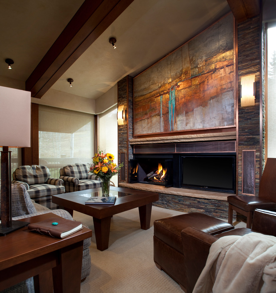 Photo of a mid-sized contemporary enclosed family room in Denver with carpet, a standard fireplace, beige walls, a metal fireplace surround and a freestanding tv.